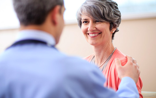A proton center physician placing his hand on a female patient's shoulder.