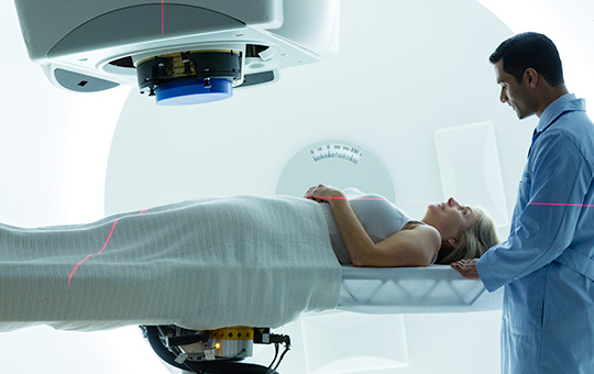 A proton physician holding the head of a female patient during proton treatment.