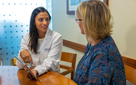Northwestern Medicine Proton Center physician Dr. Thukral talking with a blonde female patient with a blue patterned shirt.