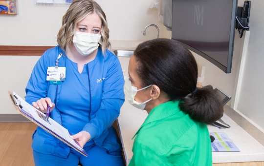 A female nurse discussing paperwork with a female patient.