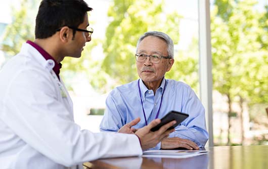 A male Proton therapy physician discussing proton therapy with an elderly male patient.