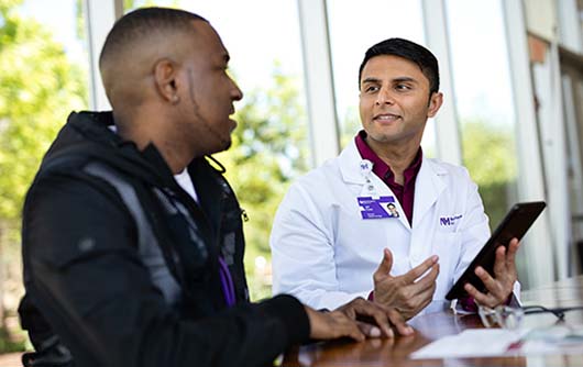 A male Proton therapy physician having a conversation with a male proton therapy patient.