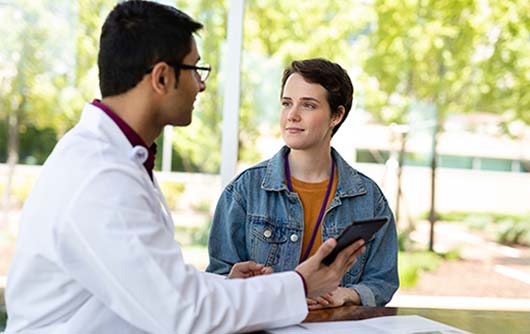 A male Proton therapy physician discussing scans with a young woman.