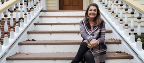 Wendy, a Proton Center patient, sitting on wooden steps outside and smiling at the camera.