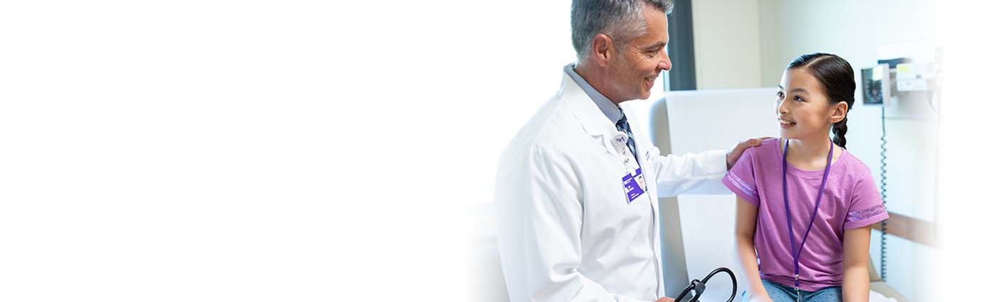 A male Proton therapy physician discussing treatment with a child patient.