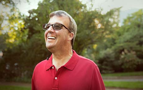 A gentleman in a red shirt outside smiling.